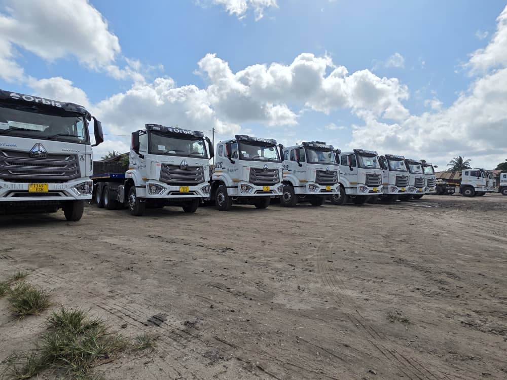 Orbis trucks lined up in the yard under a cloudy sky